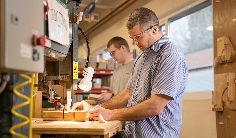 Two men drilling parts for Community Playthings furniture.