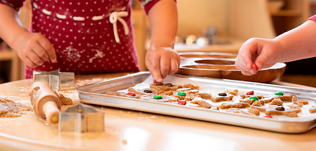 children putting cookies on tray