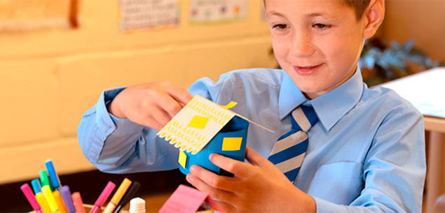 primary-aged boy crafting a house with cardboard tube