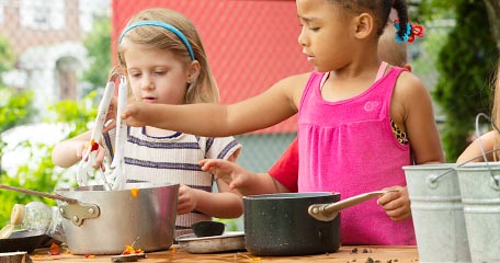 Two children outdoors mixing something in two pots