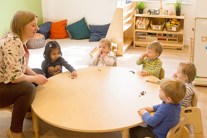 toddlers and teacher eating at a community playthings round multitable