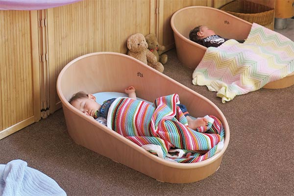 two children sleeping in coracles with bamboo panels in the background