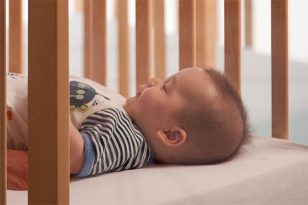 baby in crib looking at carer