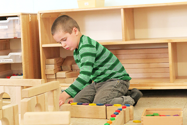 a boy is playing with unit blocks in a construction corner