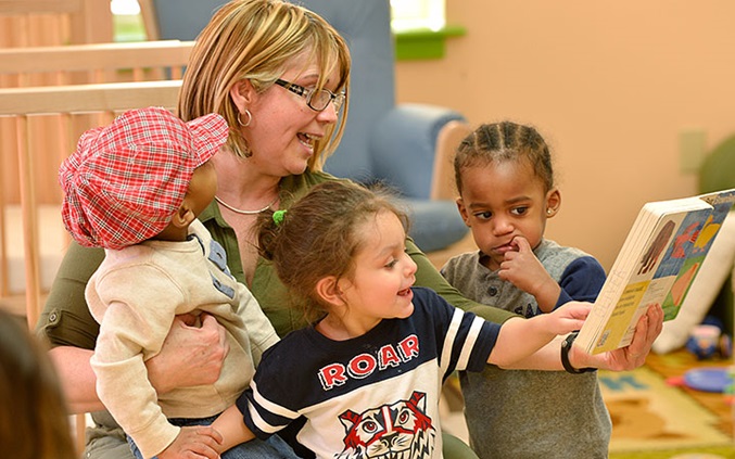 An early years teacher is reading to children