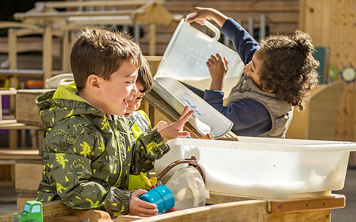 Preschool children wearing jackets and playing with water in the Outlast Cascade.