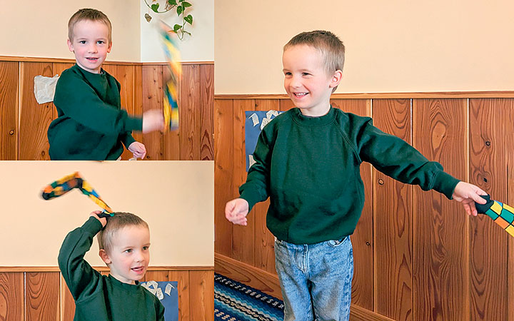 boy wearing green school sweater and happily waving a coloured sock in the air