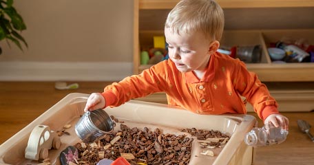 boy playing with woodchips in a sensory table
