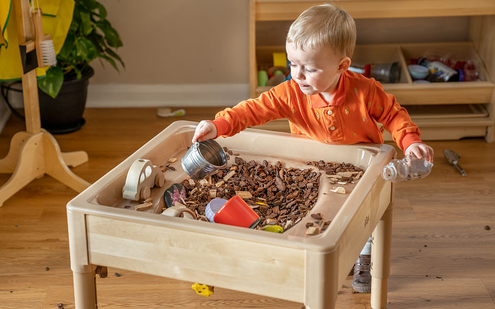 boy playing with woodchips in a sensory table