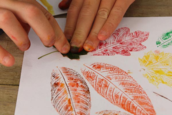 Autumn leaf prints on paper with child’s hands