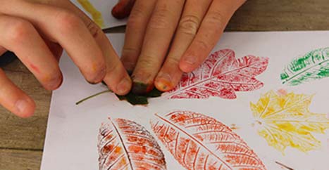 Child's hand printing with autumn leaves