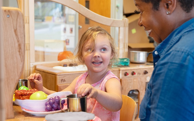 Girl sitting at table looking at teacher