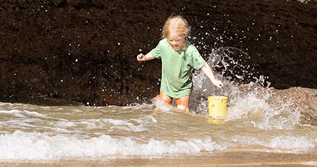 Young girl holding a bucket in the waves