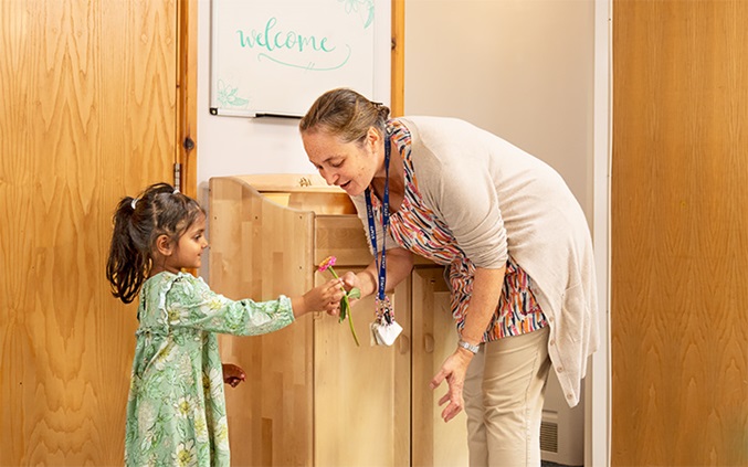 Girl showing a flower to her teacher