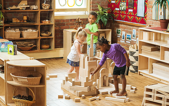 Three children playing with wooden blocks in the construction corner of an early years classroom
