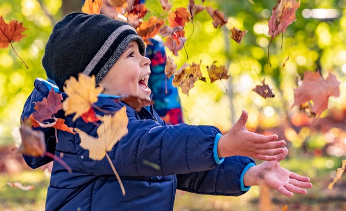 child catching autumn leaves