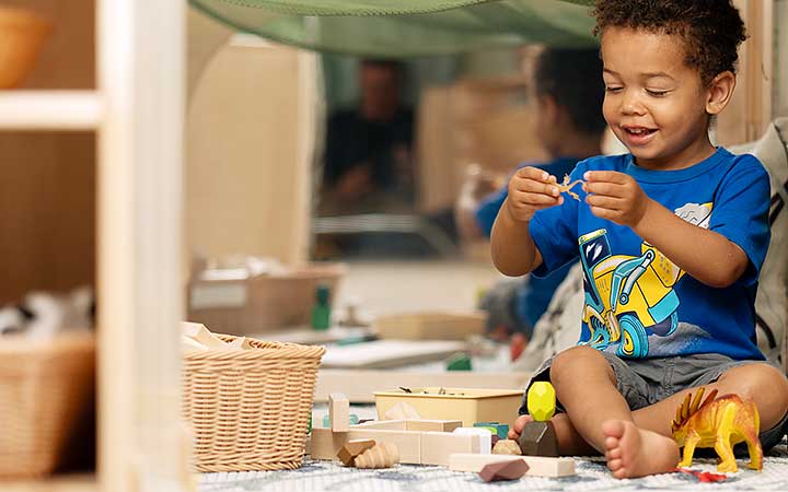 A child in a cosy space playing with community playthings mini unit blocks and toy animals.