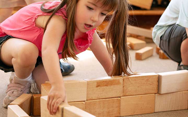A girl building a wall with community playthings unit blocks.