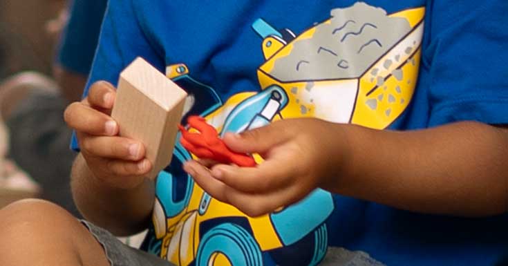 A child holding one small community playthings mini unit block