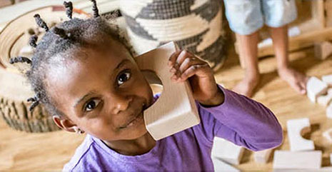 girl playing with wooden block as a telephone