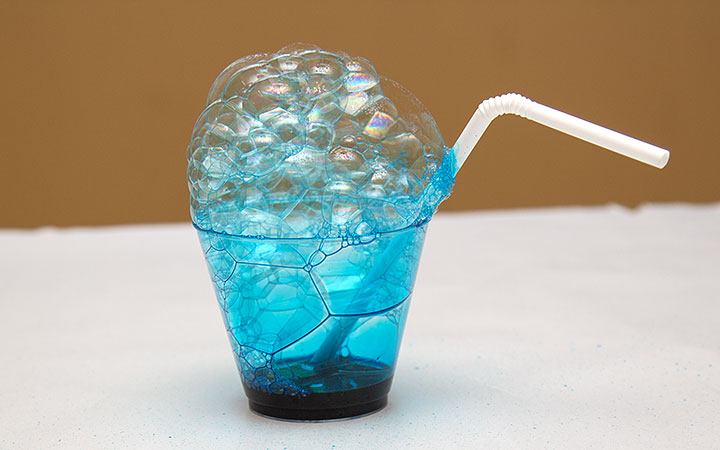 a cup with a straw, some dark blue liquid and lots of blue bubbles