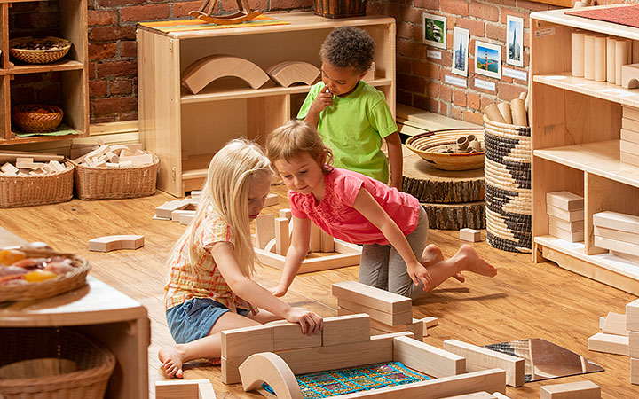 Three children playing with wooden blocks in construction corner