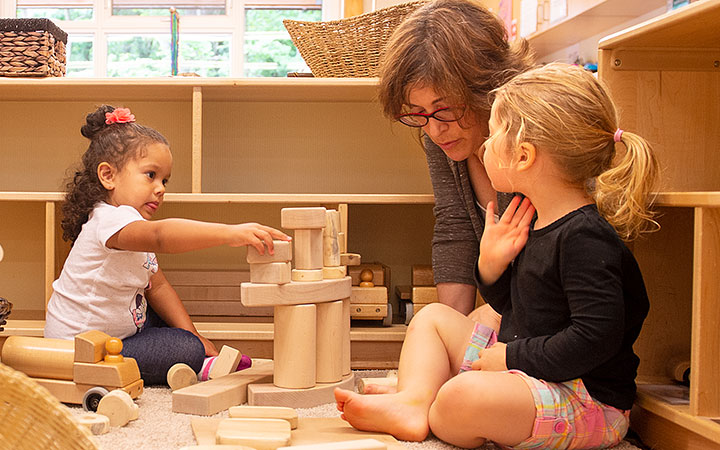 Teacher and two children building with wooden blocks