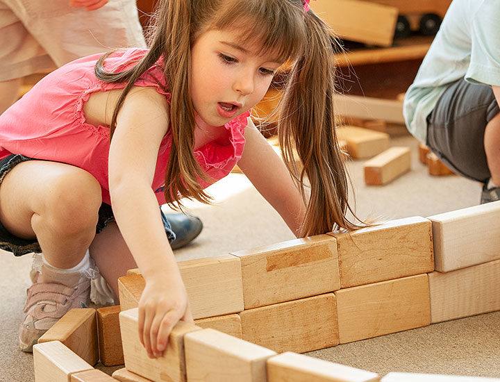 Girl building wall with wooden blocks