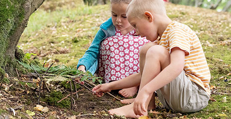 Two children building an outdoor fairy garden