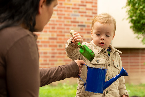 A little boy is filling earth into a watering can