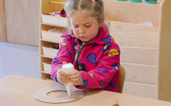 Girl squirting glue onto cardboard ring