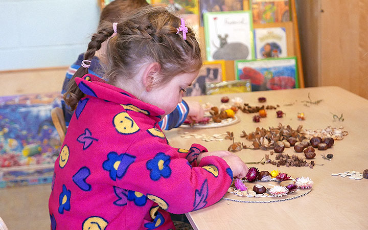 Girl at table working on nature wreath