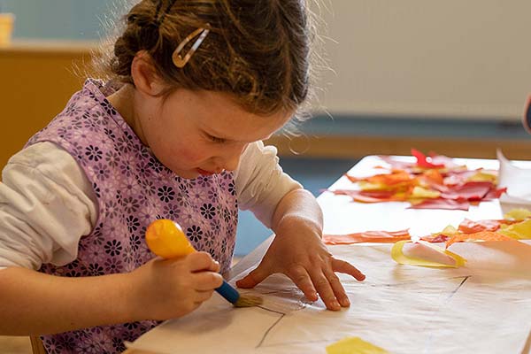 girl spreading glue on paper