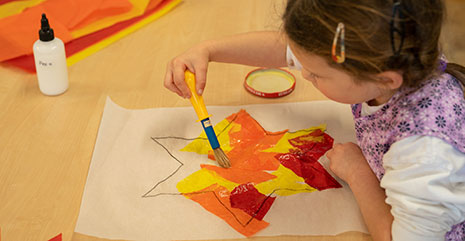 child creating a transparent star with coloured paper
