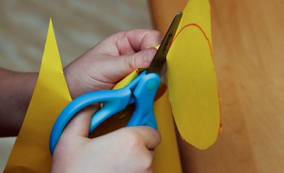 Child's hands with scissors cutting a circle out of a piece of paper