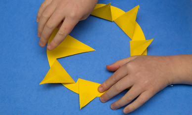 Child's hands folding the points of the star to the outside of the circle