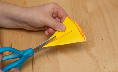 Cutting into the point of the folded paper with scissors