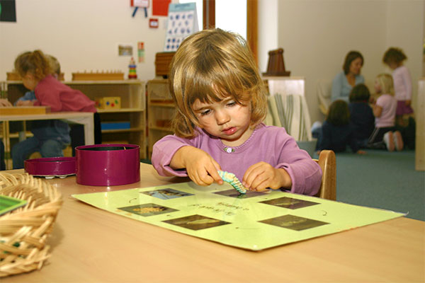 a nursery aged girl doing an art project at a table