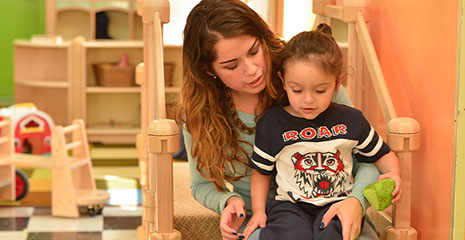 A nursery teacher is talking with a small child