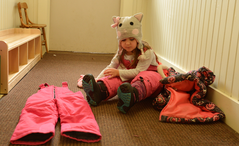 Girl changing into snowsuit, exemplifying transitions in an early years context