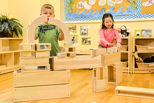 two children playing with hollow blocks and unit blocks