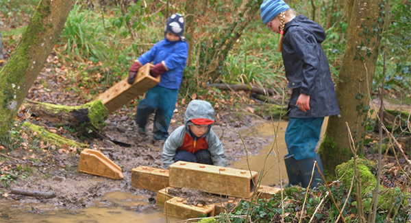 three children playing with Outlast blocks in a small stream