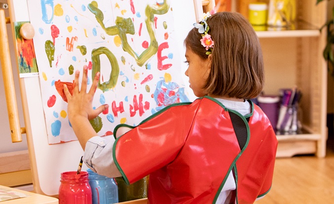 girl finger painting on easel