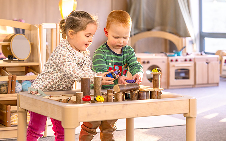 Two toddlers playing with small logs and bugs