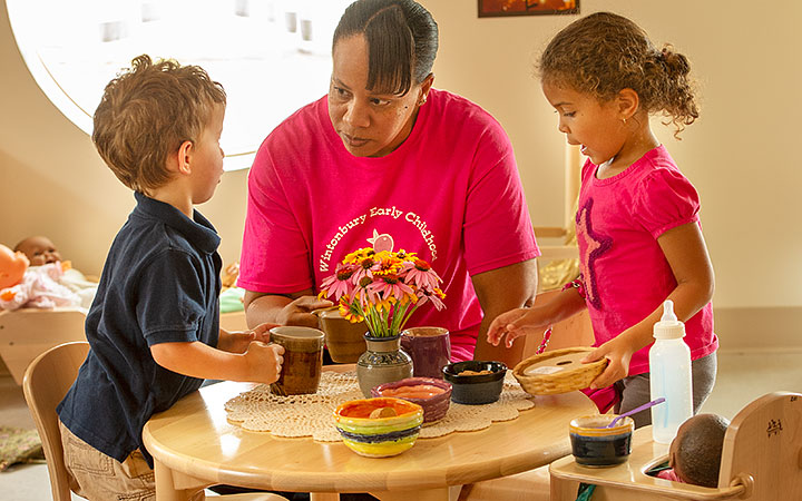 two children with teacher at a play table