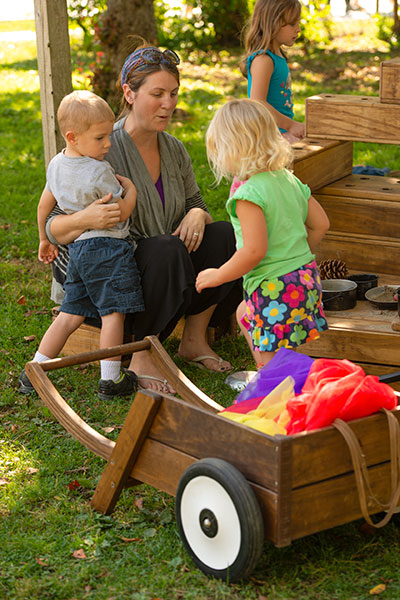 nursery teacher with two children in outdoor environment