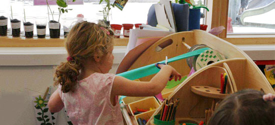 A girl is getting art materials from an art storage shelf