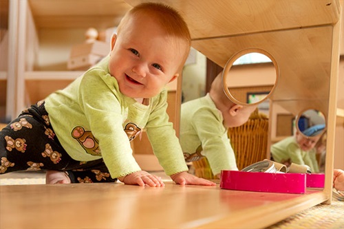 baby crawling past the mirror in a baby shelf