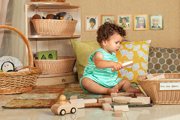 baby playing with a basket of mini unit blocks