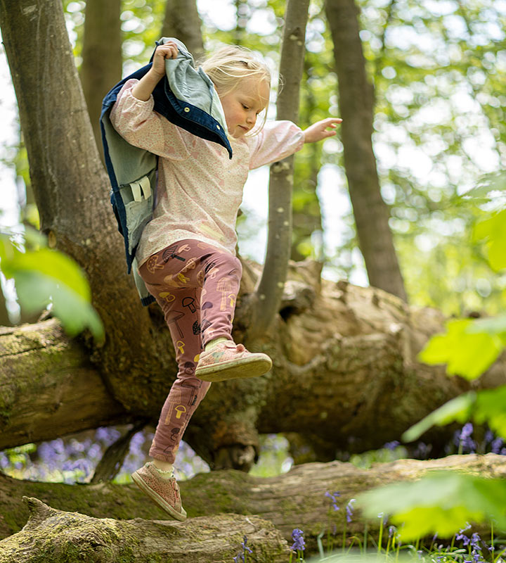 girl jumping off fallen tree